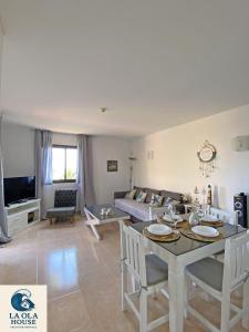 una sala de estar con una mesa y un sofá en La Ola House Precioso apartamento con piscina, en Corralejo