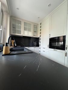 a kitchen with white cabinets and a black counter top at Apartament Helton Hel in Hel