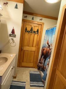 a bathroom with a door with a deer on the wall at Camp Quityerbellyachin in Greenville +8 photos