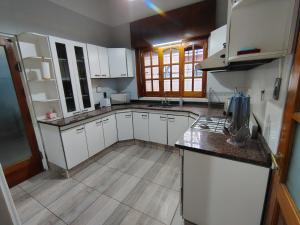 Una cocina con gabinetes blancos y encimera. en Casa Milo, en Mendoza