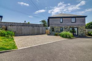 a stone house with a fence and a driveway at Sandy Cove in Penzance