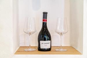a bottle of wine and two wine glasses on a shelf at ŽIŽULA Rooms in Vela Luka