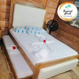 a white bed with blue pillows and a fan at Tropical Beach in Playa Blanca