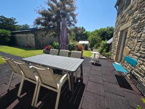a table and chairs and an umbrella on a patio at Authentique maison bretonne avec jardin fleuri in Saint-Thonan