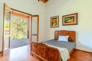 Un dormitorio con una cama y una puerta corrediza de vidrio. en Quinta da Baronesa 2 - Sapucai Mirim, en Sapucaí-Mirim