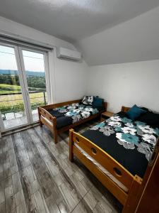 two beds in a room with a large window at Villa Melek in Bihać +4 photos