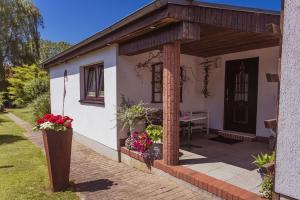a small white house with a porch with flowers at Abendsonne in Stralsund