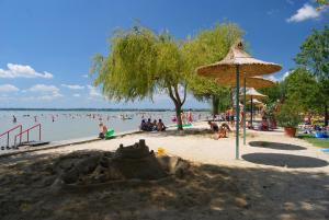 a sand castle on a beach with people in the water at Frankie Holiday Apartment I. in Balatongyörök