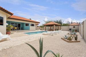 a backyard with a pool and chairs and a house at NEW 3BR 2BA Private Villa with Spacious Garden in Noord