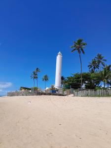 a lighthouse sitting on the beach with palm trees at Pousada Farol das Tartarugas in Praia do Forte