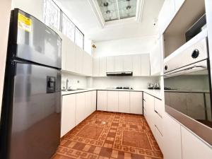 メデジンにある5BR Poblado 80s Mansion with Private Pool ACの白いキャビネットと黒い冷蔵庫のあるキッチン