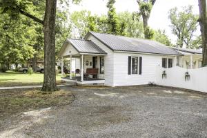 ein weißes Haus mit einem Baum davor in der Unterkunft The 1950s Retro Riverside Cottage in Dardanelle