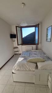 une chambre avec un grand lit avec une grande fenêtre dans l'établissement Tracastello Home House with terrace e garage, à Riomaggiore
