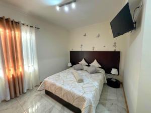 a bedroom with a large bed and a television at Cozy Ensuite Room Near Funchal Center WiFi in Funchal