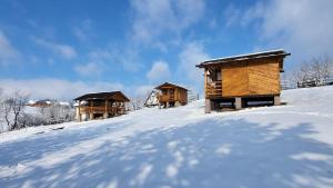 three wooden huts on top of a snow covered hill at Complex CRAI Varciorog in Vîrciorog