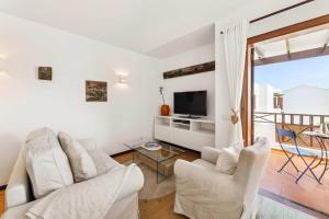 een woonkamer met 2 witte stoelen en een tv bij El Nido Seafront Hideaway by Bayside in Playa Honda