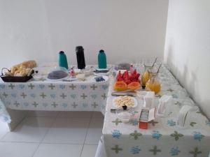 a table with a white table cloth with food on it at Oluap Pousada Mairiporã in Mairiporã