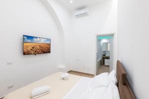 a white room with a bed and a tv on the wall at Luxury Royal House 3 in Palermo