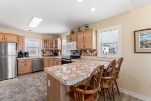 a kitchen with wooden cabinets and a large island with chairs at Everlasting Moon in Rodanthe +24 photos