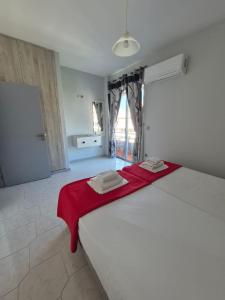 a bedroom with a white bed with a red blanket on it at Maritina Apartments in Ixia