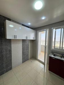 a kitchen with white cabinets and a large window at Panoramic Family Apartment Agadir New in Agadir