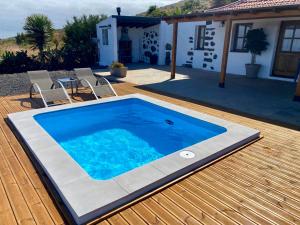 ein Pool auf einer Terrasse mit Stühlen und einem Haus in der Unterkunft Finca Malu in Garafía