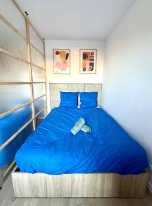 a bedroom with a blue bed with a book on it at La maison colorée proche de Paris in Romainville
