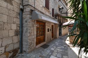 Un edificio de piedra con una puerta de madera en una calle. en Andreis Luxury Retreat, en Trogir