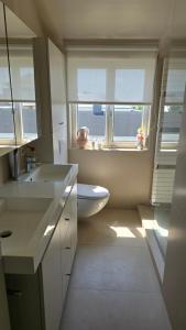 a bathroom with a toilet and a sink and two windows at Sea Home in Middelkerke +35 photos