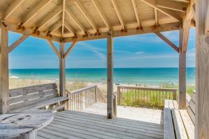 a wooden gazebo with a bench and the beach at Four Roses in Kill Devil Hills