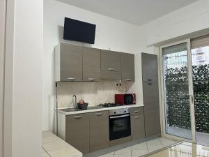 a kitchen with brown cabinets and a tv on the wall at B&B mirò e appartamenti in Marina di Gioiosa Ionica