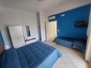 a bedroom with two beds and a blue wall at B&B mirò e appartamenti in Marina di Gioiosa Ionica