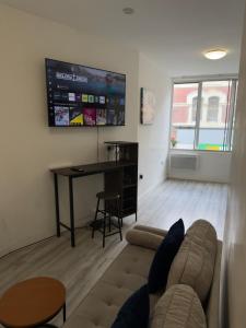 a living room with a couch and a desk and a television at Central Wigan Stay in Wigan