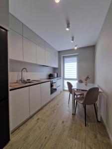 a kitchen with white cabinets and a table and chairs at Apartament on StyleUp StayRent Lutsk in Lutsk