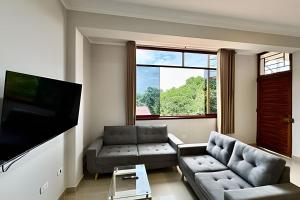 Una sala de estar con un sofá y un televisor de pantalla plana. en Vive a 5min centro 2HAB con A/C Terraza y Parrilla, en Tarapoto
