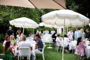 a group of people sitting at tables under white umbrellas at The Maidstone Hotel in East Hampton