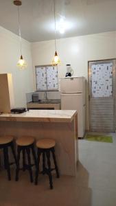 Una cocina con una encimera con taburetes y un refrigerador. en Vivenda Paz do Jubim, en Salvaterra