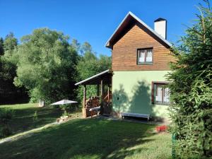a house with a yard with a bench and an umbrella at Chata Teodor in the Forest, Slovak Paradise in Betlanovce