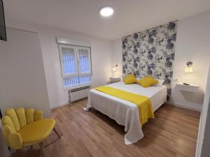 a bedroom with a bed and a yellow chair at El Rinconin I in Cangas de Onís