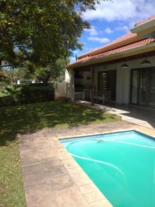 a swimming pool in front of a house at Pecanwood Villa with lake view in Hartbeespoort