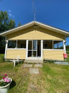 a yellow house with a table and a chair at Mansikkamökki 