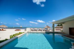 a swimming pool with a view of the beach and the ocean at Ocean's Edge Belize in San Pedro