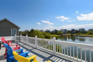 a row of colorful chairs on a deck next to the water at Gone Fishin in Nags Head