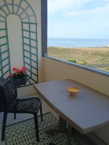 a table and a chair in a room with a window at Bord de plage, thalasso et vue mer ! in Cabourg