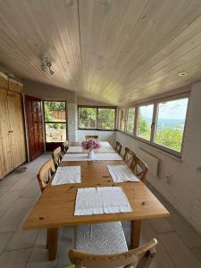 a large wooden table in a room with windows at Forestin Vendégház in Nagymaros