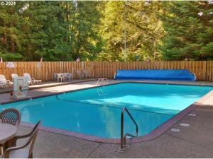 ein blauer Swimmingpool mit Stühlen und einem Holzzaun in der Unterkunft Pet Friendly Retreat Hot Tub & Games On Mt Hood in Mount Hood Village
