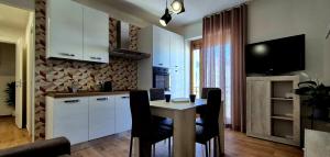 cocina con mesa con sillas y TV en Must Apartaments, en Polignano a Mare