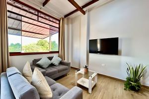 Una sala de estar con un sofá y un televisor. en Vive a 5min centro 2HAB con A/C Terraza & Parrilla, en Tarapoto