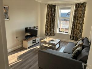 a living room with a couch and a tv at 2 bedroom first floor flat- Bonnie Stays in Troon