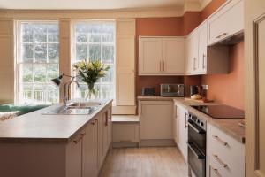 a kitchen with white cabinets and a sink at Walcot Townhouse 3 bedroom in Bath